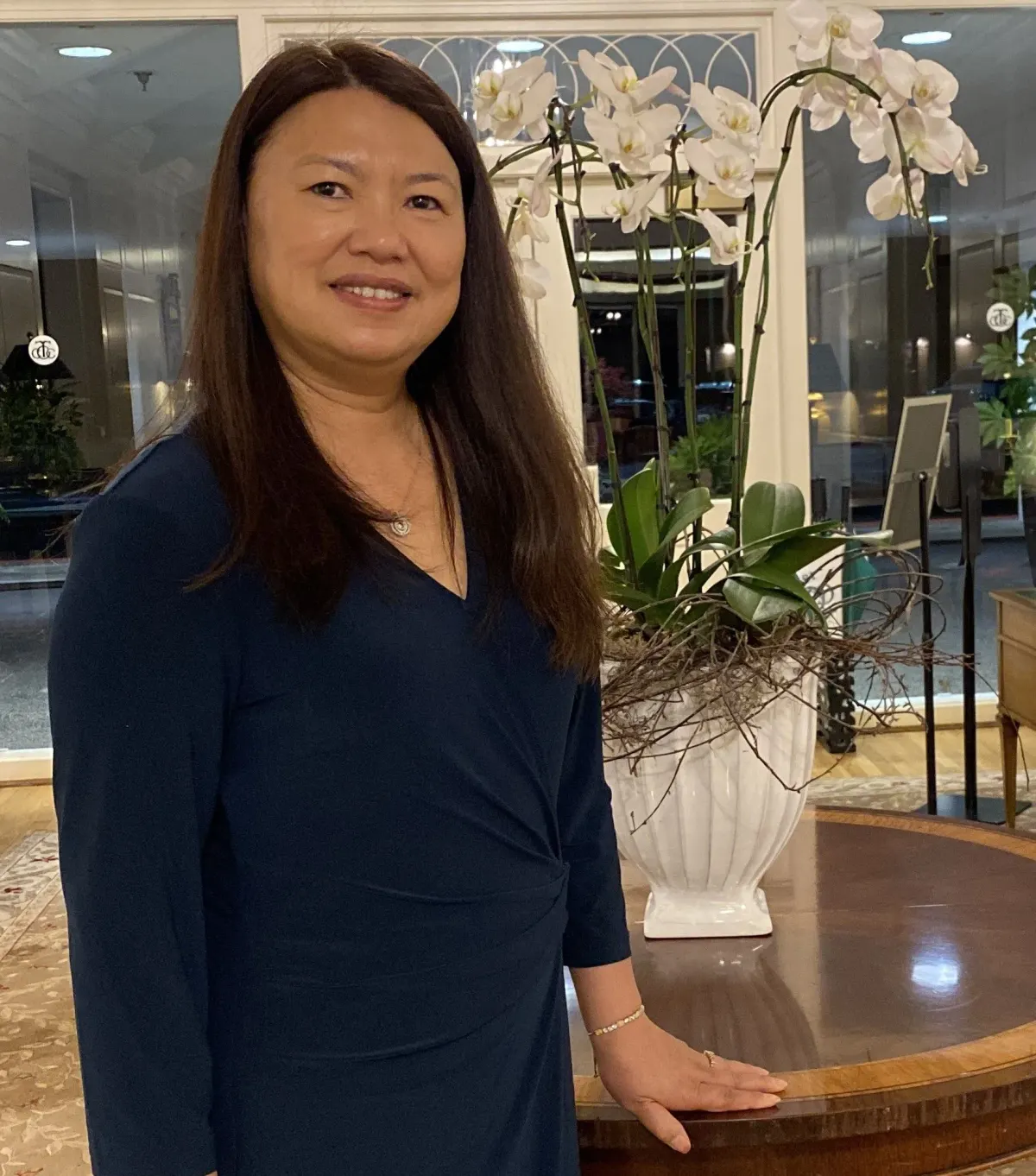Lisa Thungc, Iu Mien Language Services co-founder, standing beside white orchids