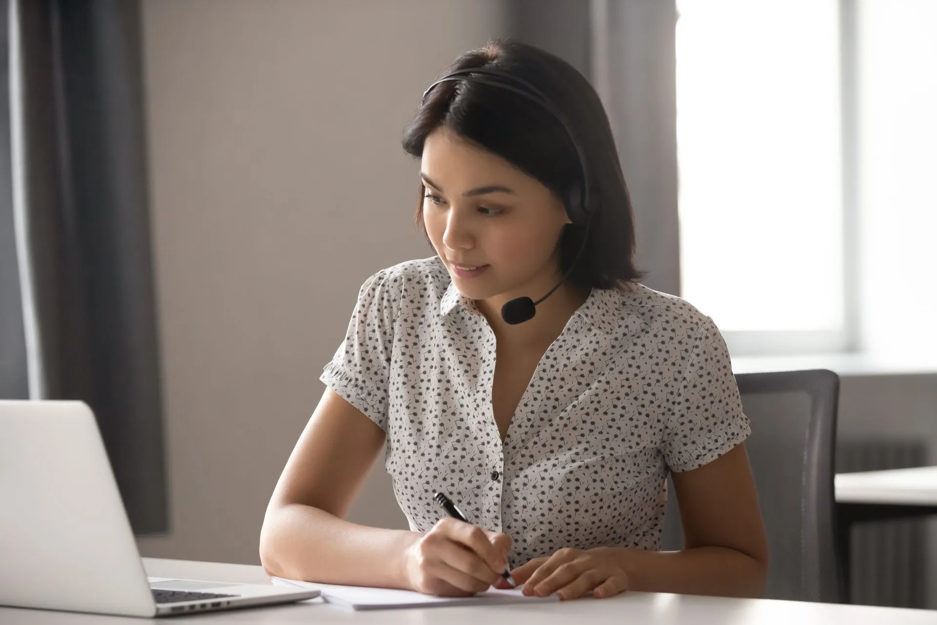 Mien translator wearing a headset and working at a laptop on translated materials